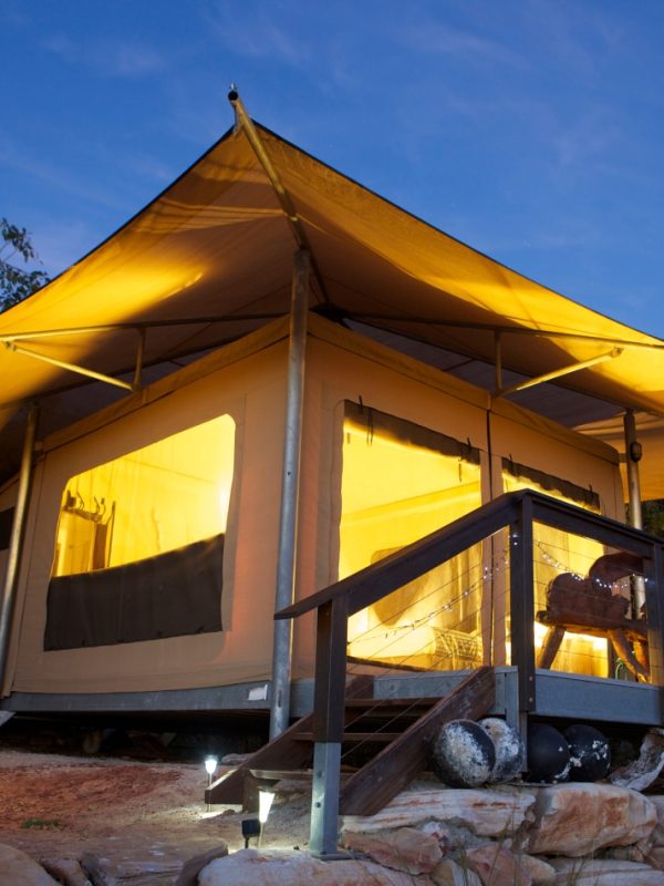 A Diver's Creek Glamping Safari Tent glows with it's ambient lighting within at dusk n the unique, rugged landscape of the Diver's Creek site at Cygnet Bay Pearl Farm.