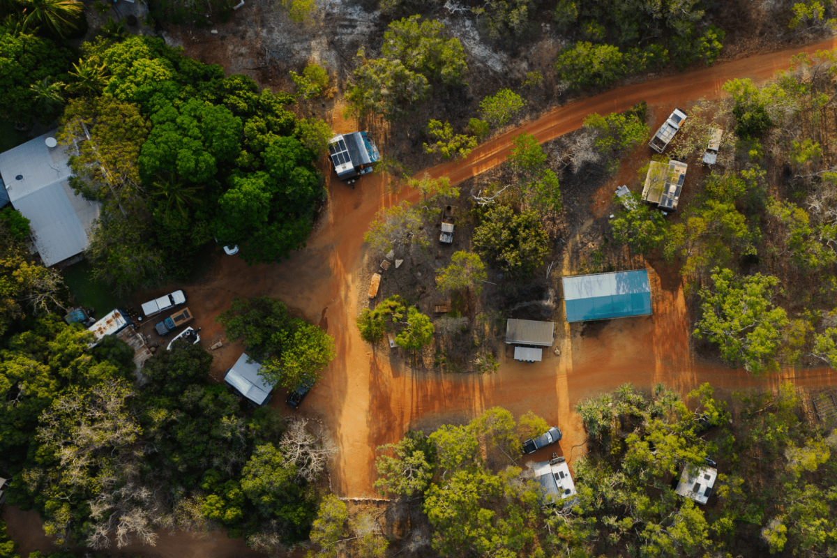 An aerial view of the stunning, rugged landscape of the Dampier Peninsula's terrain and dirt roads to multiple camping and caravan locations for vacationers to pitch a tent up at. Each camp site is surrounded by native, Australian plants that create privacy for the campers - a truly serene experience.