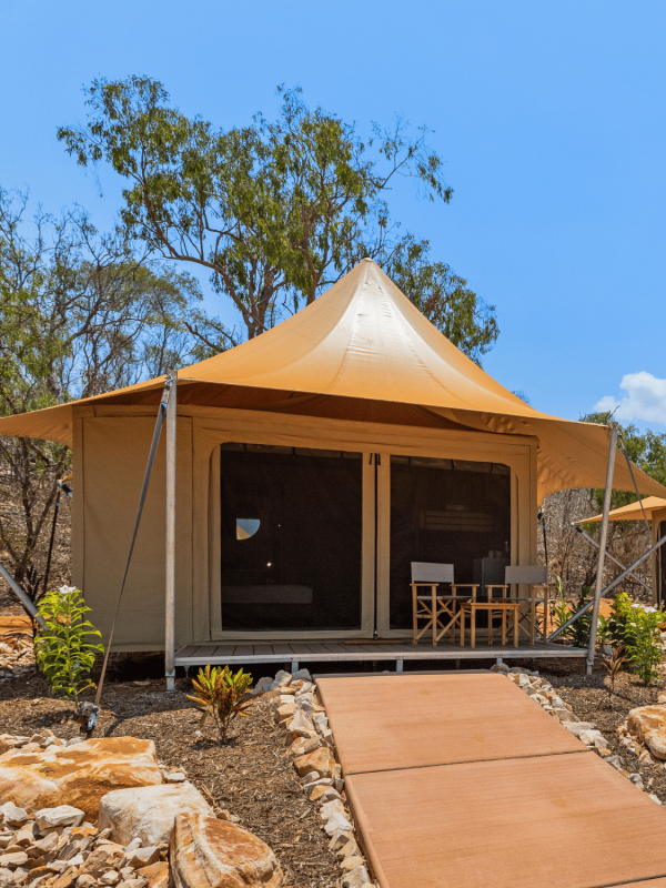 An eco tent in our Pearler's Village with some seating at the front of the tent, shaded by the sun.