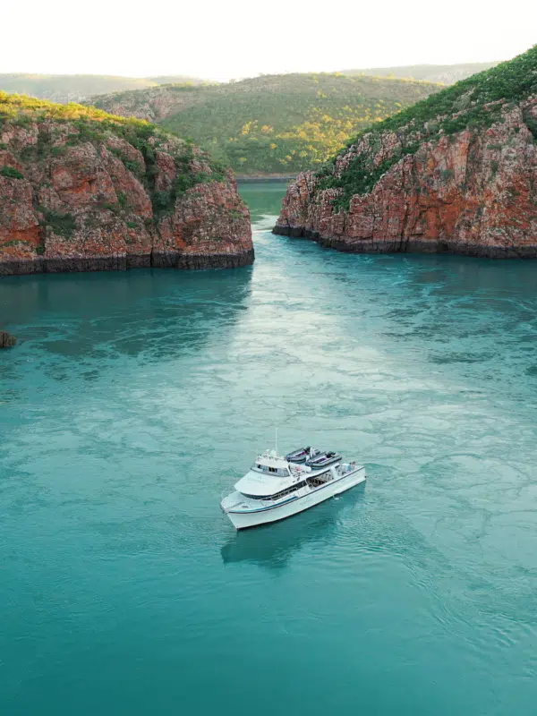 A boat sits on the calm, turqouise waters in the foreground, in front of the iconic Horizontal Falls. The Horizontal Falls are an unusual natural phenomenon on the coast of the Kimberley region in Western Australia, where tidal flows causes waterfalls on the ebb and flow of each tide.