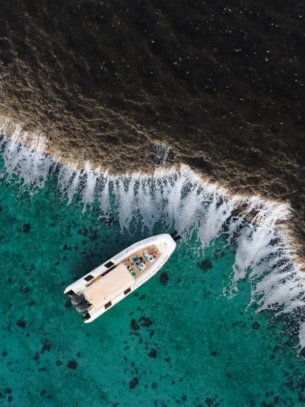 A Cygnet Bay boat sits idly next to the iconic Waterfall Reef, spilling water during the low tide of the ocean. The guests on the boat bare witness to this unique natural phenomenon and are in awe of it's cascading waterfall effect.