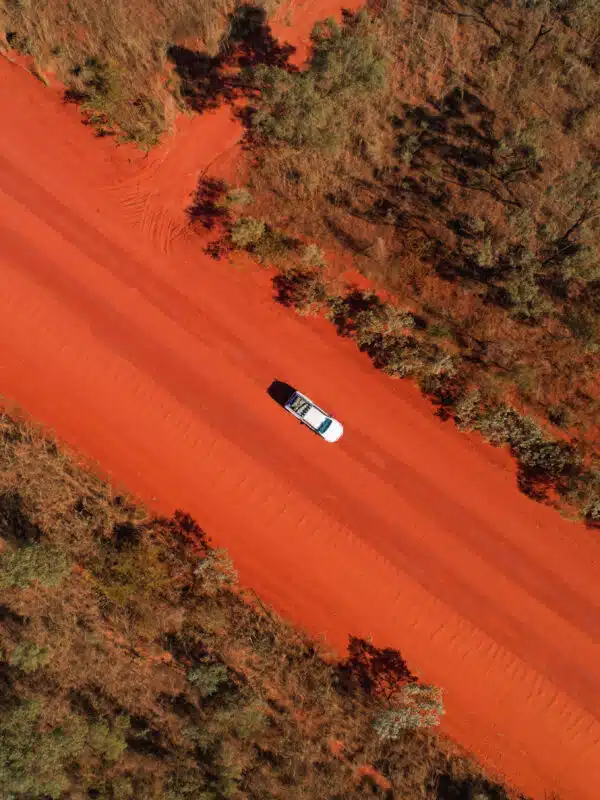 A hired car from BroomeBroome Car Rentals drives to Cygnet Bay Pearl Farm on the red pindan dirt road.