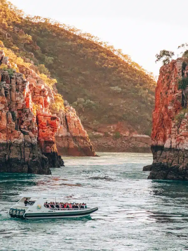 A boat sits on the calm, turqouise waters in the foreground, in front of the iconic Horizontal Falls. The Horizontal Falls are an unusual natural phenomenon on the coast of the Kimberley region in Western Australia, where tidal flows causes waterfalls on the ebb and flow of each tide. Horizontal Falls Soar, Cruise & Overnight Stay.
