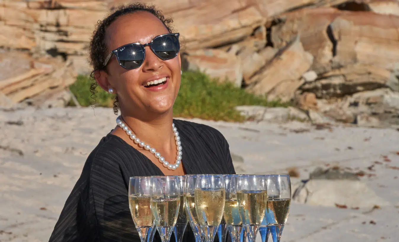 A tour guide holds a tray of champagne, ready to hand out to arriving guests, and is adorned in her Cygnet Bay grown pearl strand.
