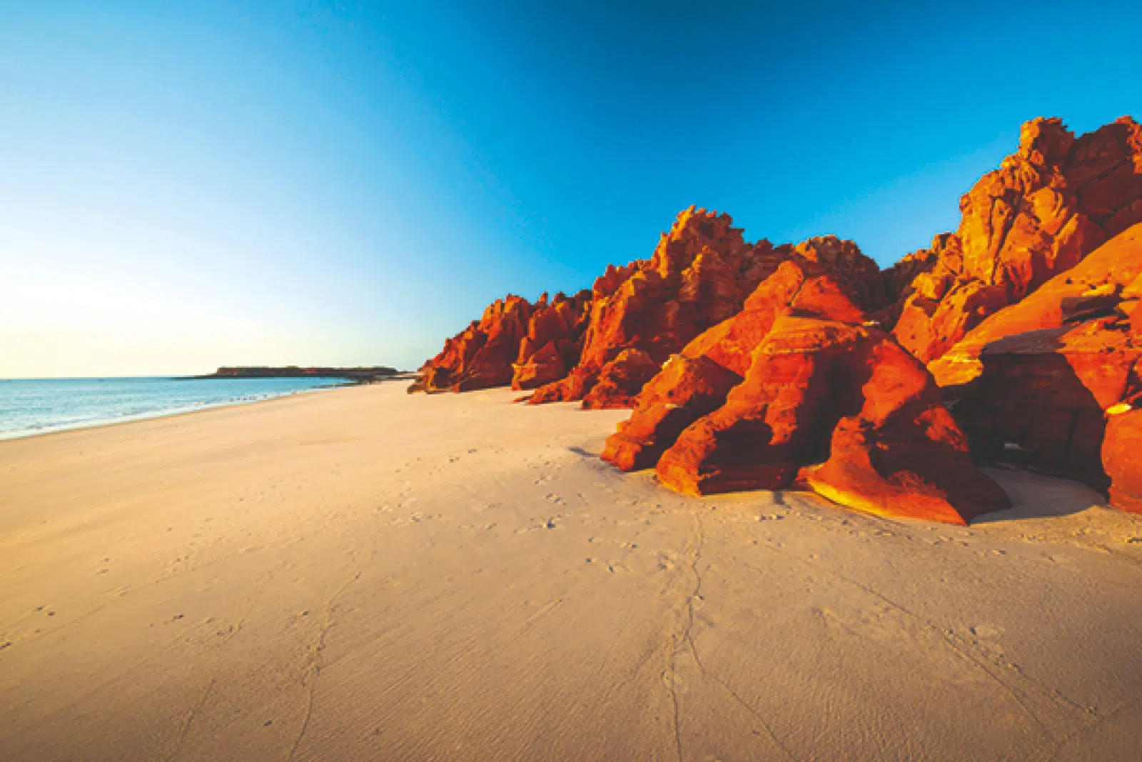 A Kimberley beach, where the red rocky landscape meets the turquoise waters.