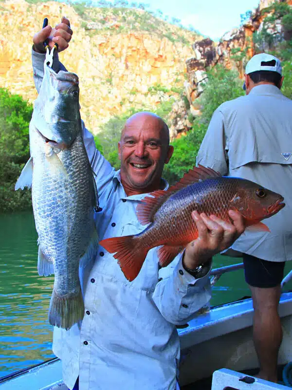A man holds two fish he has freshly caught.