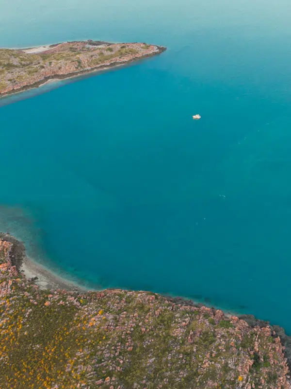 A lone boat sits on the calm, serene waters of the Kimberley during an Island Explorer tour.