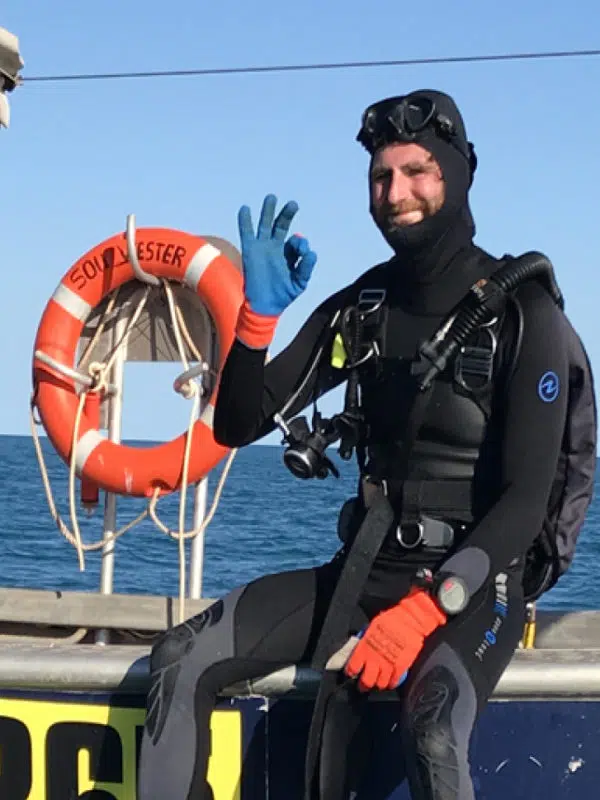 A diver sits on the edge of a pearling boat, ready to harvest Australian South Sea Cygnet Bay pearl oysters.