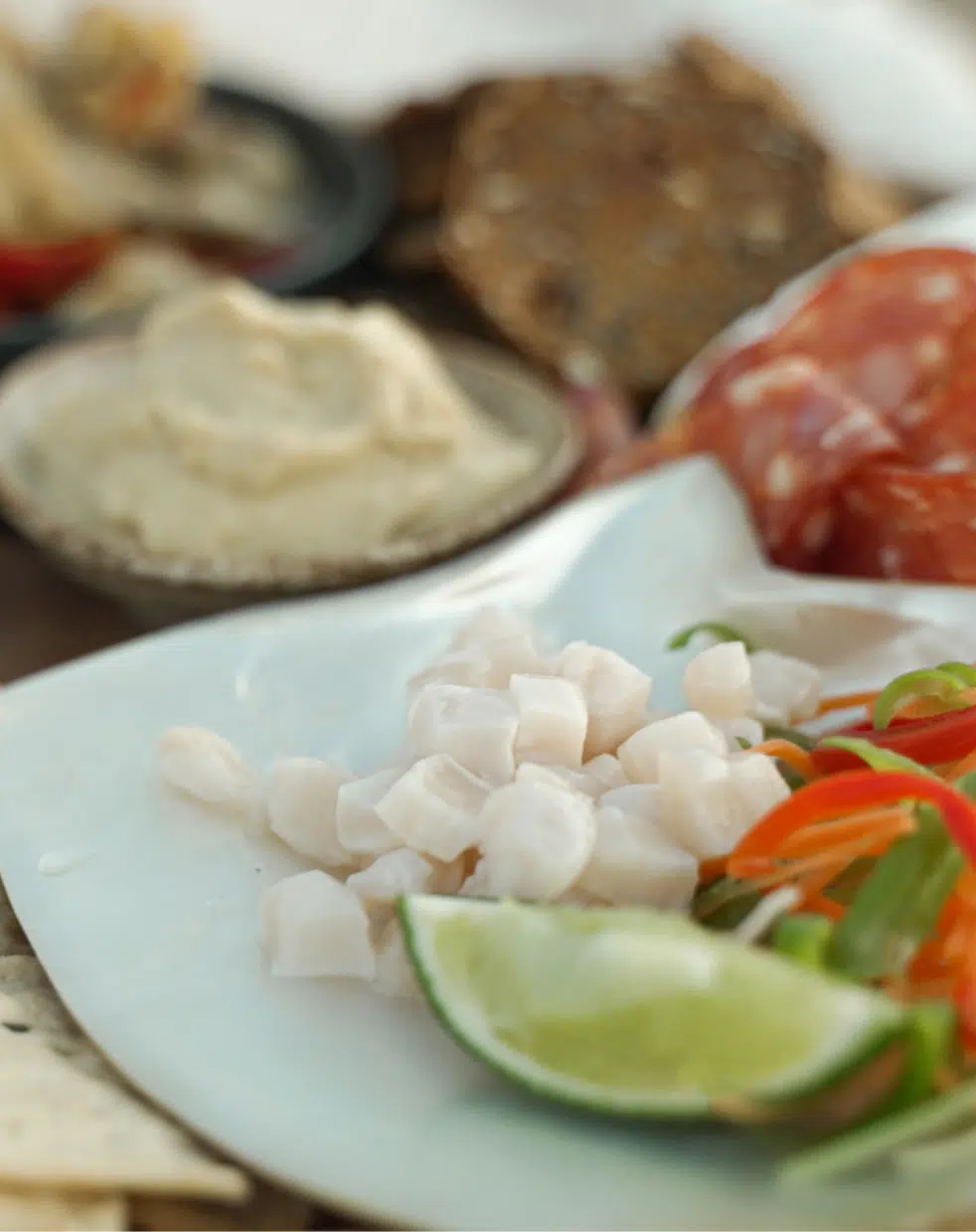 Australian South Sea pearl meat served on an Australian South Sea Mother of Pearl shell, alongside some pickled vegetables, a lime for serving. Alongside this Cygnet Bay grown delicacy are other dips, meats and spreads. Our Pearl Meat.