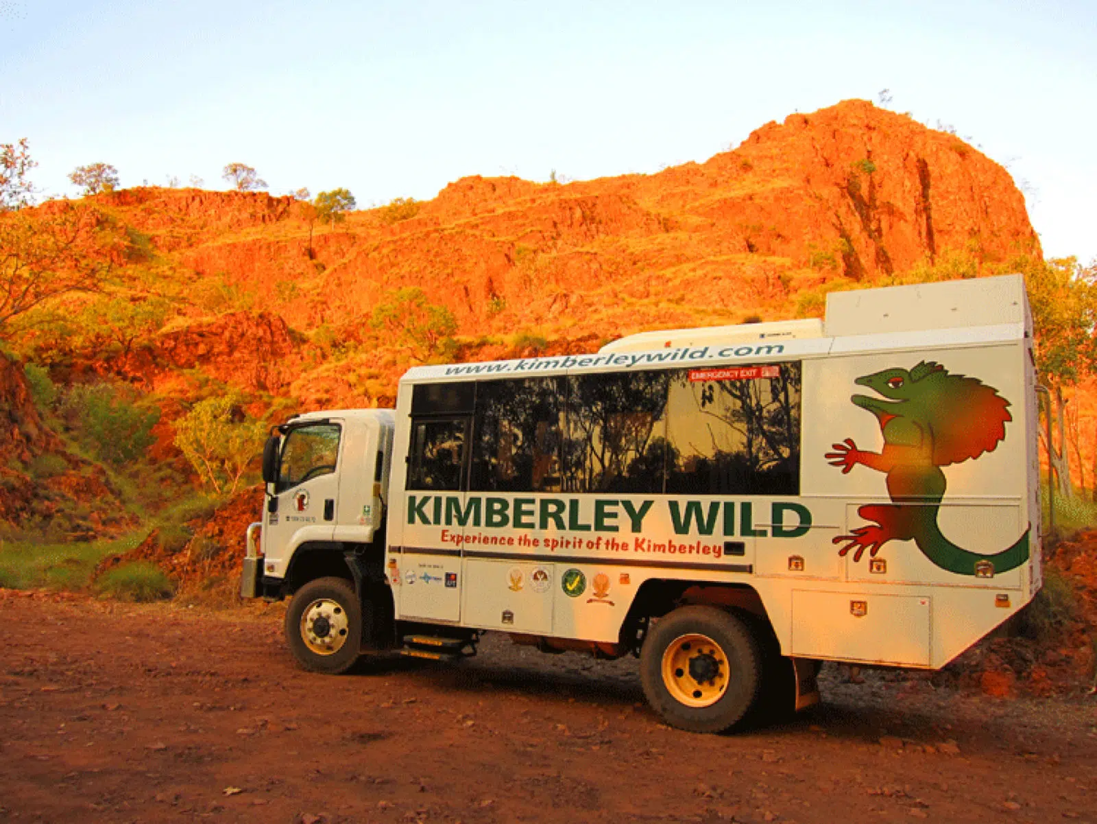 A Kimberley Wild truck sits on a dirt road, with the stunning Kimberley gorges in the distance.