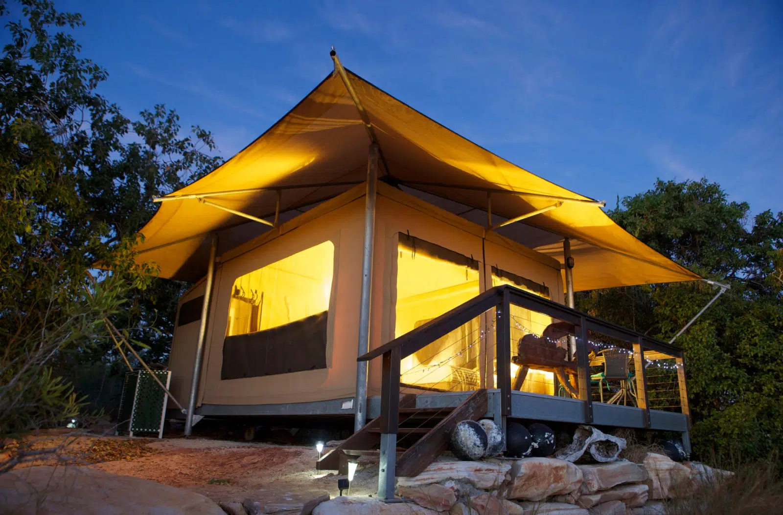 A Diver's Creek Glamping Safari Tent glows with it's ambient lighting within at dusk n the unique, rugged landscape of the Diver's Creek site at Cygnet Bay Pearl Farm.