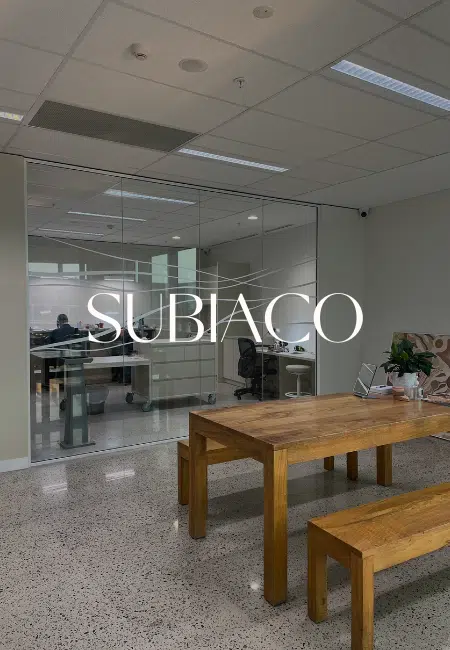 A consultation table sits in the centre of the Perth Studio, ready for a client to join in a consultation or to pick up their jewellery piece. Behind the table, in another room but seen through a window, is the jewellery workshop with two jewellers carefully crafting our Pearls of Australia jewellery pieces.